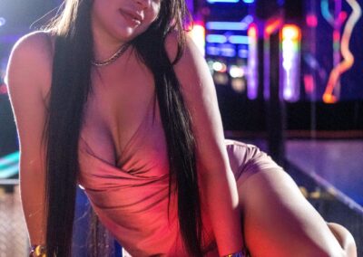A woman with long black hair posing on a bar